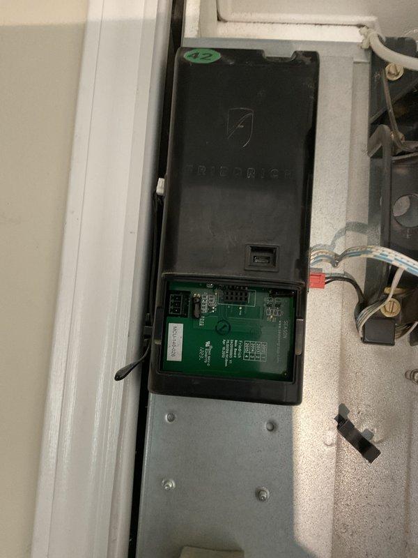 Conducted site assessment for commercial RTU replacement at facility with existing ductless mini-split system in storage area. Documented current equipment configuration including control module and circuit board assembly, photographed installation conditions, and gathered specifications for new rooftop unit estimate preparation.