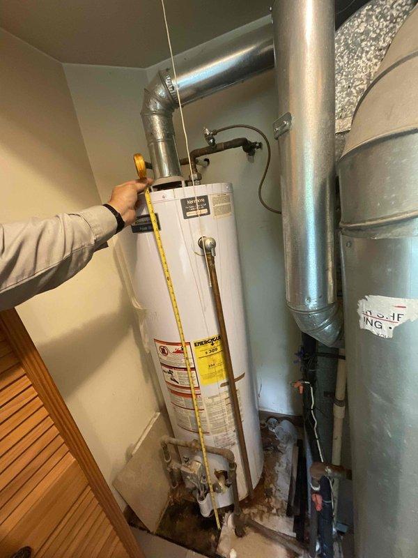Responded to no cooling call at residential property. Upon arrival, performed diagnostic inspection of HVAC system and related mechanical equipment in utility area. Measured and documented existing water heater and HVAC components, including ductwork configuration and equipment spacing. Photographed installation for service records showing water heater, gray HVAC unit with insulation, metallic ventilation ductwork, and plumbing connections. Coordinated service visit during caregiver availability window to ensure property access and customer communication.