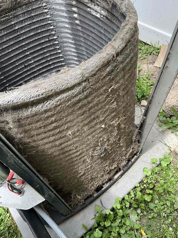 Performed comprehensive A/C tune-up service on outdoor condenser unit. Upon arrival, found unit heavily coated with accumulated dust, dirt, and fibrous debris throughout exterior surfaces and cooling fins. Completed thorough coil cleaning to remove significant buildup that was restricting airflow and reducing system efficiency. Cleaned condenser coils using appropriate methods to restore proper heat transfer capability. Removed vegetation growth around unit base and cleared debris from surrounding area to ensure adequate clearance and airflow. Unit operational following service with improved airflow through cleaned coil surfaces.