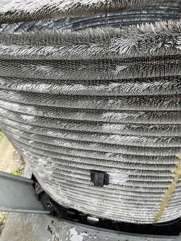 Performed comprehensive A/C tune-up service on outdoor condenser unit. Upon arrival, found unit heavily coated with accumulated dust, dirt, and fibrous debris throughout exterior surfaces and cooling fins. Completed thorough coil cleaning to remove significant buildup that was restricting airflow and reducing system efficiency. Cleaned condenser coils using appropriate methods to restore proper heat transfer capability. Removed vegetation growth around unit base and cleared debris from surrounding area to ensure adequate clearance and airflow. Unit operational following service with improved airflow through cleaned coil surfaces.