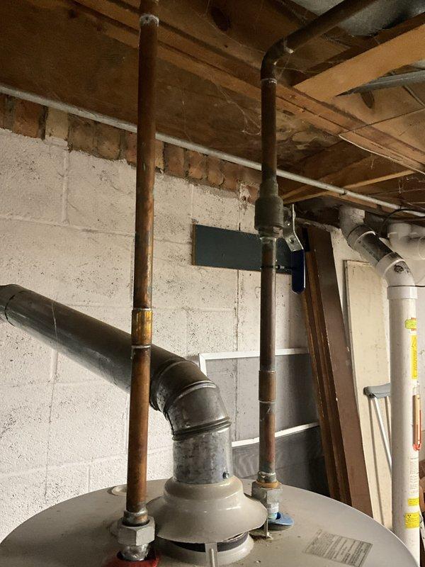 Completed on-site assessment of existing 50-gallon gas water heater and related plumbing components in residential basement. Evaluated current installation including water heater unit, gas shutoff valve, and two basement saddle valves for replacement. Documented existing conditions through photographic documentation showing exposed ceiling joists, copper piping connections, concrete block foundation walls, and current water heater configuration. Provided separate estimates for replacement of gas water heater unit, gas shutoff valve upgrade, installation of leak protection pan, and replacement of both saddle valves to bring system up to current plumbing standards in 50-year-old home.