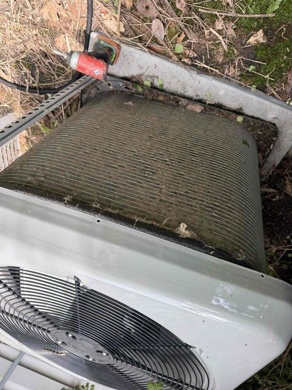 Returned to address previous frozen evaporator coil issue on residential air conditioning system. Upon inspection, discovered outdoor condenser coil heavily contaminated with organic growth, moss, algae, and debris accumulation restricting airflow through fins. Condenser coil showed significant dark discoloration and biological buildup across horizontal fin surfaces. Performed thorough condenser coil cleaning to restore proper airflow and heat transfer capability. Cleared surrounding area of leaves, twigs, and organic debris that had accumulated around unit base. Verified refrigerant lines and connections secure. System operational following coil cleaning with improved airflow through condenser unit.