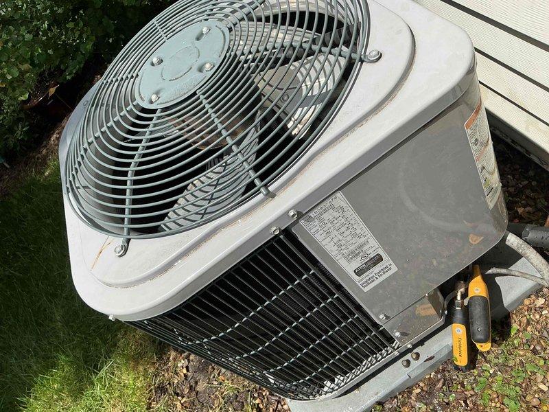 Completed comprehensive BFMA tune-up service on a 7+ year old residential air conditioning system. Performed full system inspection of outdoor condenser unit, which showed signs of age-related weathering and rust staining on exterior panels. Verified thermostat operation with Nest unit displaying proper temperature control at 65 degrees. Inspected condenser coils through protective grilles, checked fan motor assembly and grille components, and evaluated overall unit performance to ensure optimal cooling efficiency for continued operation.