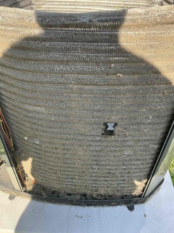 Completed comprehensive BFMA tune-up service on residential air conditioning system with equipment age of 1+ years. Performed standard maintenance protocol including inspection of condenser unit, evaluation of coil conditions, and assessment of refrigerant lines. Both the cylindrical top-discharge condenser coil and rectangular coil assembly showed significant accumulation of dirt, dust, and debris on fin surfaces, which can restrict airflow and reduce system efficiency. Documented equipment condition through photographic records showing outdoor unit mounted on concrete pad with visible weathering and contamination on coil surfaces. All components were evaluated for proper operation and system readiness.