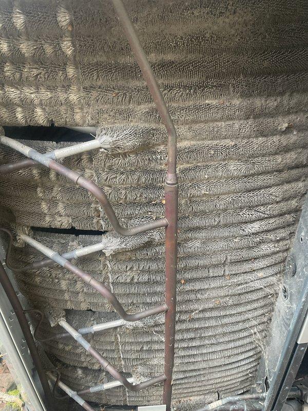 Completed comprehensive BFMA tune-up on a 9+ year old air conditioning system. Performed thorough inspection of outdoor condenser unit, including evaluation of evaporator coil condition with visible dust and debris accumulation on aluminum fins and copper refrigerant lines. Documented equipment condition through photography, noting normal operational wear patterns and environmental particle buildup on heat exchanger surfaces consistent with unit age and service history.