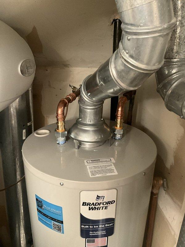 Completed installation of a 40-gallon Bradford White water heater in a confined utility space. Due to tight clearances, coordinated removal of the existing water heater and furnace replacement to facilitate proper positioning and installation of the new unit. Connected copper supply lines with dielectric unions and installed galvanized metal venting ductwork per manufacturer specifications and local code requirements.
