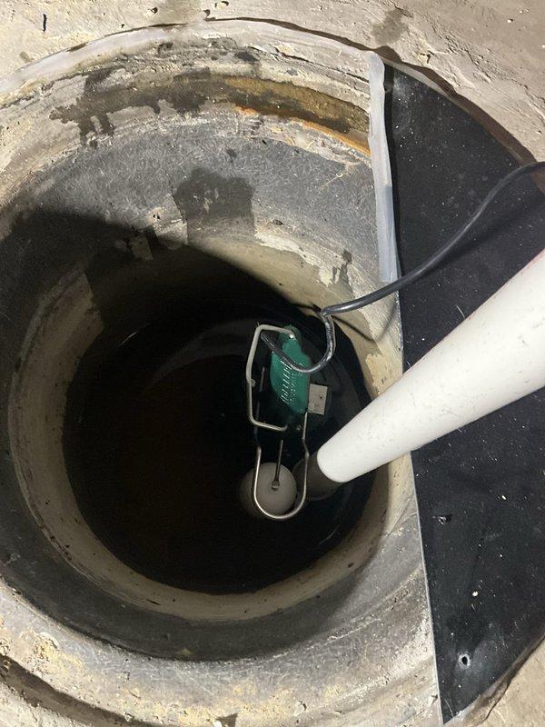 Removed sealed sump pit lid and extracted existing sump pump and check valve from concrete sump basin. Installed new 1/2 horsepower sump pump with discharge piping system, including new check valve, PVC pipe, fittings, and mounting hardware secured to floor joists. Tested pump operation for proper cycling and discharge flow, then resealed sump pit lid upon completion. All removed equipment was properly disposed of, and installation includes 3-year warranty on pump with 1-year parts and labor coverage.
