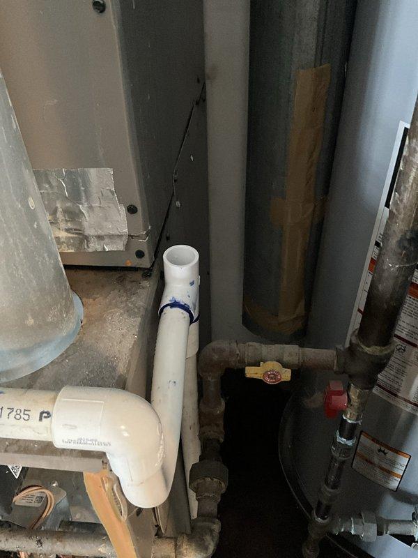 Responded to no cooling call on 15+ year old residential HVAC system with reported water leak of unknown origin. Upon inspection, discovered significant corrosion on refrigerant lines and internal piping within the air handler compartment, with rust and yellowish deposits indicating long-term moisture exposure. Traced water leak source to drain system issues, evidenced by PVC drainage components in mechanical area showing signs of improper pitch or blockage. Documented equipment condition including Guardian-branded unit with aged internal components, corroded piping, and compromised insulation. Recommended system evaluation for refrigerant line integrity and complete drain line service to address both cooling failure and active water leak.