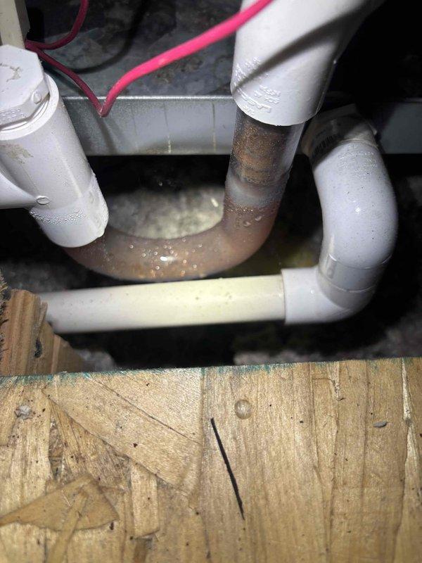 Completed A/C tune-up service for non-member system located in attic space. Upon inspection, identified significant crack in ceiling directly below air handler installation point. Documented existing condensate drain assembly showing corroded metal pipe section within P-trap configuration, which exhibited moisture accumulation and oxidation. Photographed HVAC equipment installation including filter drier, refrigerant lines with pink electrical wiring, and PVC condensate piping mounted on plywood platform. Verified attic access is safe with adequate structural beam support for service access. Customer advised to contact for follow-up regarding ceiling damage assessment.