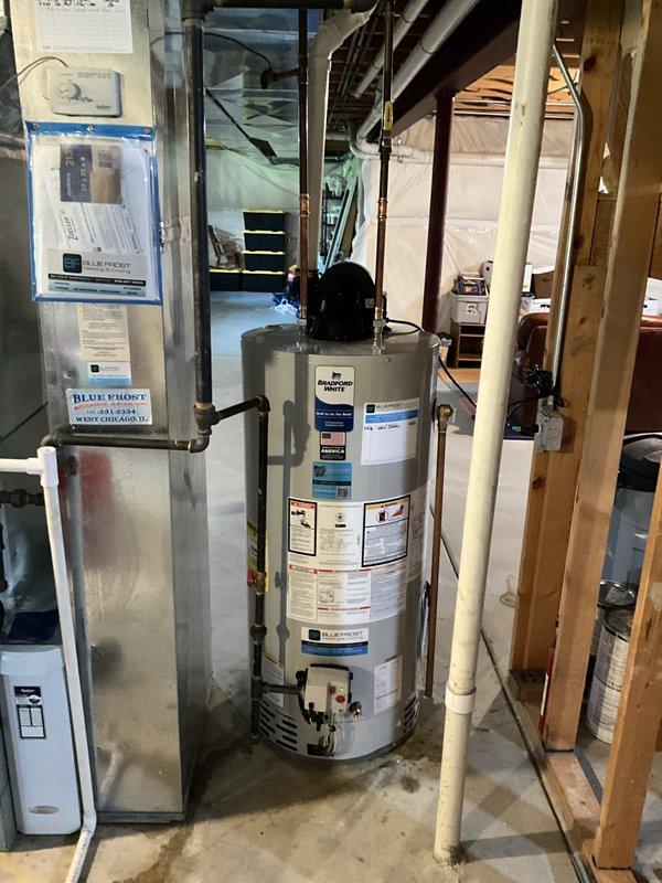 Installed a 50-gallon tanked water heater in residential basement utility area, replacing existing unit. Connected copper supply lines and black pipe fittings to top of unit, ensuring proper integration with existing plumbing infrastructure and overhead piping. Installation completed with all manufacturer specifications met and unit operational alongside existing HVAC equipment.