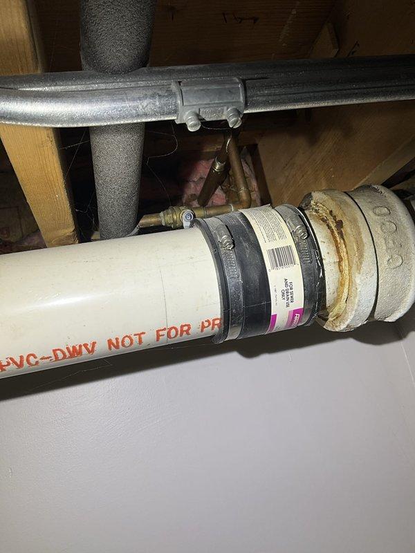 Responded to service call for leaking outside spigot and noisy toilet. Upon inspection, accessed crawlspace plumbing infrastructure to assess drainage and supply line conditions. Documented existing PVC-DWV drainage system configuration, noting proper pipe installation and fittings beneath structure. Identified corrosion present on pipe connections requiring attention. Examined coupling connections with rubber fittings and metal clamps, observing deterioration at junction points. Inspected multiple plumbing lines including copper supply lines and insulated pipes in utility space. Captured photographic documentation of plumbing assembly and corrosion areas for service records. Addressed toilet noise issue and exterior spigot leak as reported.