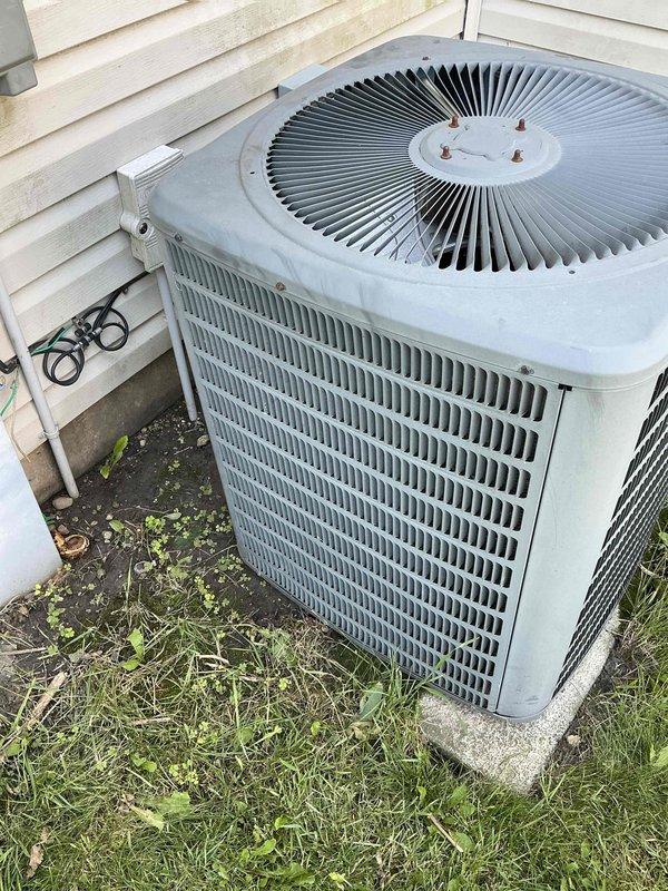 Conducted on-site evaluation of 12-year-old central air conditioning system to provide replacement estimate. Inspected outdoor condenser unit with cylindrical design and top-mounted fan assembly, noting weathered exterior finish consistent with age and outdoor exposure. Assessed electrical disconnect box, conduit routing, and power supply connections at exterior installation. Evaluated indoor electrical panel and existing infrastructure in basement utility area to determine compatibility requirements for new equipment installation. Documented current system configuration, mounting pad condition, and clearance specifications. Provided comprehensive equipment replacement quote including condenser unit and evaporator coil to address aging system nearing end of service life.