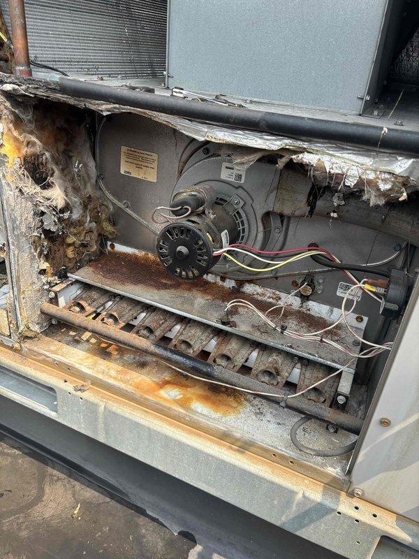 Responded to commercial AC service call for unit not cooling below 80°F despite thermostat set to 60°F. Accessed rooftop unit and discovered severely corroded blower motor assembly and deteriorated interior cabinet components with extensive rust damage throughout. Added refrigerant to system and performed necessary repairs to restore cooling operation, though unit shows significant age-related deterioration requiring monitoring for future replacement consideration.