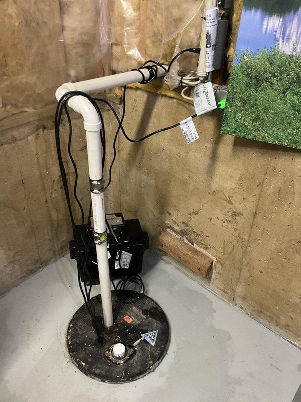 Installed a complete Zoeller drop-in sump pump system featuring both primary and backup pumps in basement sump basin. System includes white PVC vertical discharge piping with horizontal run secured to foundation wall, black electrical connections to backup battery unit, and all necessary mounting hardware. All components installed per manufacturer specifications with warranty coverage provided on pumps, charger, battery, and labor.