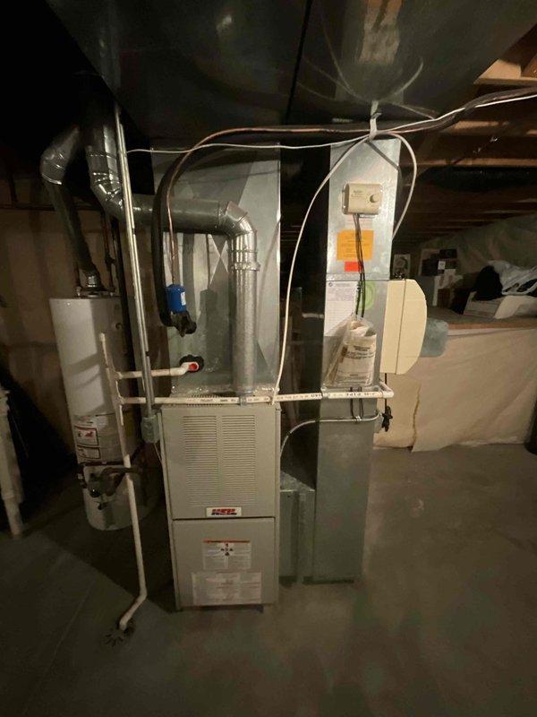 Conducted comprehensive sales estimate for complete air conditioning system and evaporator coil replacement in residential basement mechanical room. Evaluated existing white cabinet furnace unit with connected ductwork, assessed galvanized metal duct configuration extending through ceiling joists, and inspected PVC condensate drainage routing. Reviewed electrical panel capacity and circuit breaker configuration to verify adequate 15-amp circuits available for new HVAC equipment installation, noting existing AC circuit designation. Documented current system layout including ductwork connections, equipment positioning relative to water heater, and available workspace for proposed A/C and coil installation.