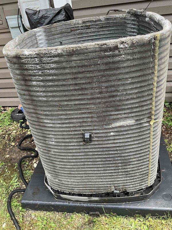 Completed comprehensive BFMA tune-up service on outdoor condensing unit with 5+ years of operation. Performed standard maintenance protocol including system inspection, coil assessment, and operational testing. Unit exhibited significant fin damage with bent and crushed sections on condenser coil, along with accumulated dirt, debris, and environmental contamination between fins. Noted deteriorated foam insulation material present on exterior coil surfaces and visible discoloration indicating age-related wear. Documented equipment condition with photographic evidence showing compromised coil integrity that may impact heat transfer efficiency and overall system performance. Recommended monitoring system performance and considering coil straightening or replacement to restore optimal airflow and cooling capacity.
