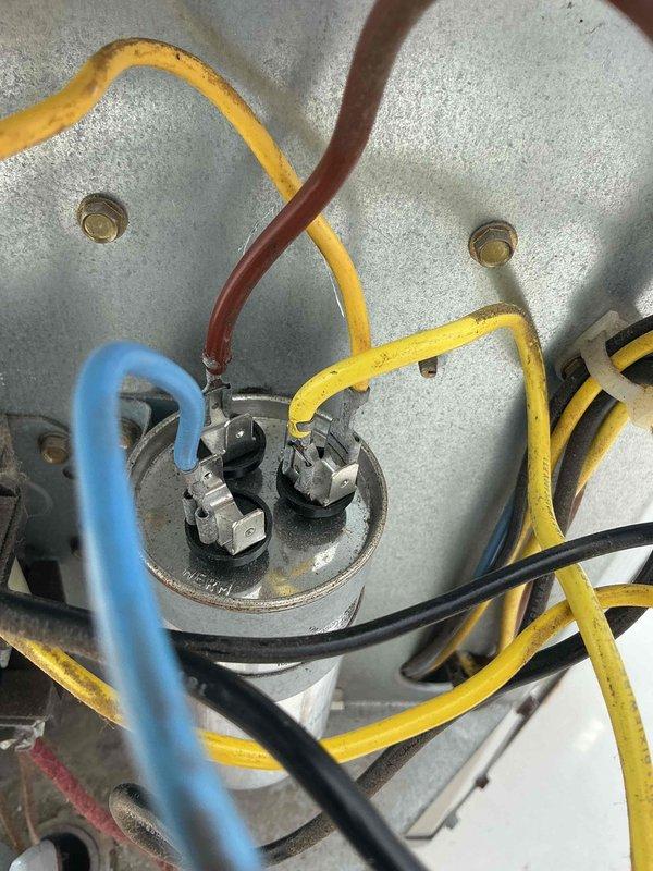 Responded to after hours emergency call for HVAC system malfunction. Upon inspection, identified faulty capacitor with loose and deteriorated electrical connections at the terminal block. Disconnected power supply, removed defective capacitor, and installed replacement unit. Reconnected all color-coded wiring to proper terminals, verified secure connections, and tested system operation. Unit restored to normal working condition and confirmed proper voltage readings across all connections.