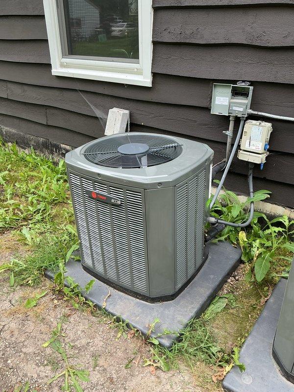 Technician returned to residential property to perform leak detection inspection on split system air conditioning unit. UV dye search conducted on outdoor condensing unit with visual inspection of condenser coil, refrigerant line connections, and compressor area. System components photographed for documentation and no active refrigerant leaks identified during inspection under UV light conditions.