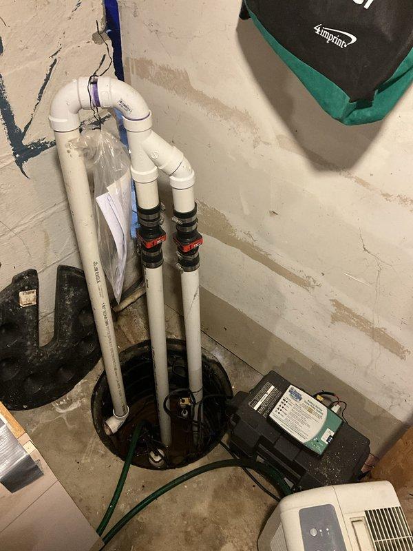 Responded to service call regarding black water discharge from well water system following water heater installation completed one year prior. Upon arrival, inspected tanked water heater installation and associated plumbing connections. Observed greasy residue on flex connectors and investigated potential contamination source affecting water quality. Examined sump pump system, pressure tank, and water heater configuration to identify cause of discoloration. Documented existing conditions including water heater with proper venting, blue pressure tank, plumbing connections, and sump pit installation with discharge piping. Assessed overall system operation and water flow characteristics to determine if issue originates from well system, sediment accumulation, or plumbing component degradation.