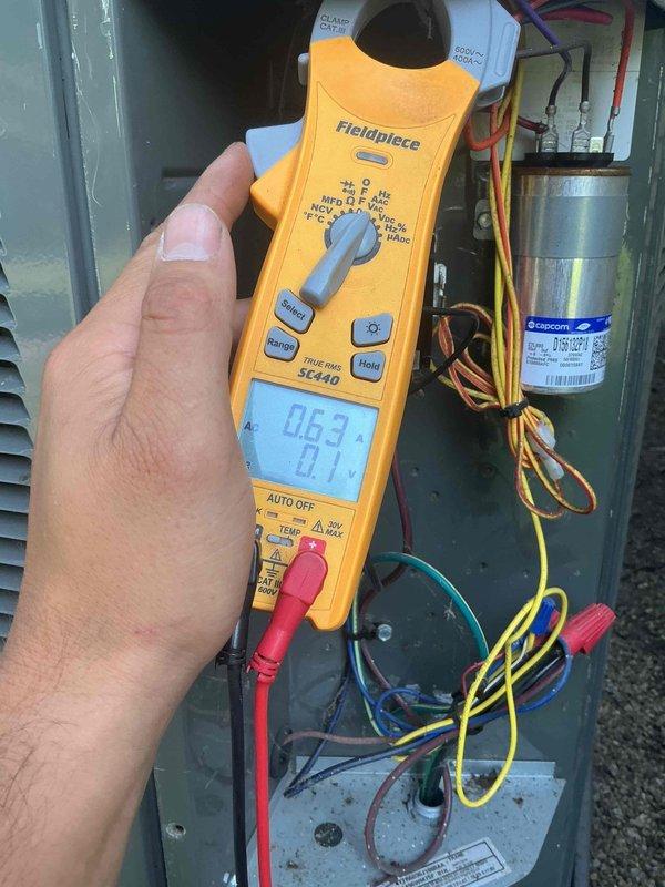 # HVAC Service Report - No Cooling Condition Resolved

Responded to residential no cooling call where client reported loss of cold air for multiple days. Upon arrival, performed systematic diagnostic evaluation of outdoor condensing unit and electrical components.

Conducted voltage and amperage testing at control panel using digital multimeter. Initial readings showed abnormal electrical values at 21.7V and 0.63A, indicating potential contactor failure. Inspected Copcom capacitor and associated wiring connections, verifying proper terminal connections and wire routing throughout the electrical panel.

Identified failed contactor as root cause of no cooling condition. Contactor showed signs of electrical failure preventing compressor and condenser fan operation. Removed defective contactor from unit and installed new Packard replacement contactor with proper electrical specifications for the system.

Verified proper amperage draw of 10.8A after contactor replacement, confirming normal 