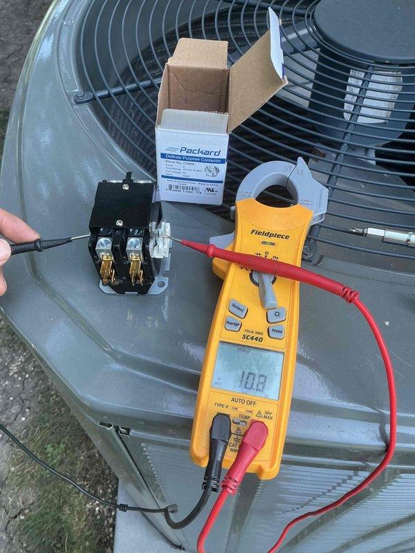 # HVAC Service Report - No Cooling Condition Resolved

Responded to residential no cooling call where client reported loss of cold air for multiple days. Upon arrival, performed systematic diagnostic evaluation of outdoor condensing unit and electrical components.

Conducted voltage and amperage testing at control panel using digital multimeter. Initial readings showed abnormal electrical values at 21.7V and 0.63A, indicating potential contactor failure. Inspected Copcom capacitor and associated wiring connections, verifying proper terminal connections and wire routing throughout the electrical panel.

Identified failed contactor as root cause of no cooling condition. Contactor showed signs of electrical failure preventing compressor and condenser fan operation. Removed defective contactor from unit and installed new Packard replacement contactor with proper electrical specifications for the system.

Verified proper amperage draw of 10.8A after contactor replacement, confirming normal 