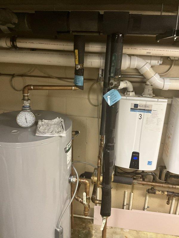 Responded to service call for lukewarm water complaints in multi-unit residential building. Upon inspection, found hybrid water heating system consisting of one tanked water heater and three wall-mounted tankless units. Tested all equipment and verified proper operation of pressure relief valves, thermostats, and heating elements on tanked unit. Checked temperature settings and functionality of all three tankless water heaters, confirmed proper ignition sequences and burner operation. Inspected all copper piping connections, pressure gauges, and isolation valves throughout the system for leaks or restrictions. Verified adequate gas supply and proper venting for tankless units. Documented existing equipment configuration and operational status with photographs for service records.