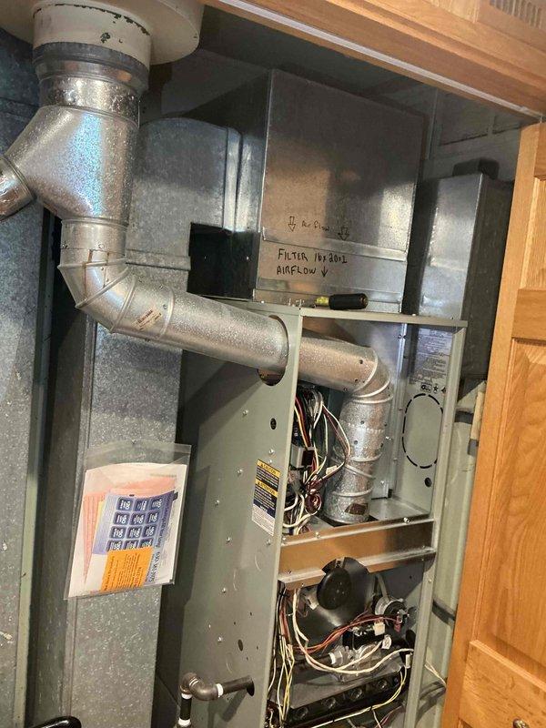 Conducted comprehensive HVAC system evaluation for air conditioning and coil replacement estimate on residential forced-air system. Existing furnace/air handler unit showing signs of operational strain with airflow concerns noted on equipment markings. Inspected internal components including blower assembly, electrical connections, and ductwork configuration. Photographed current system installation including cabinet interior, wiring harnesses, and electrical panel to document existing conditions. System currently operational but struggling to maintain adequate performance. Assessed ductwork connections, filter access, and overall equipment compatibility for proposed A/C and coil replacement recommendations.