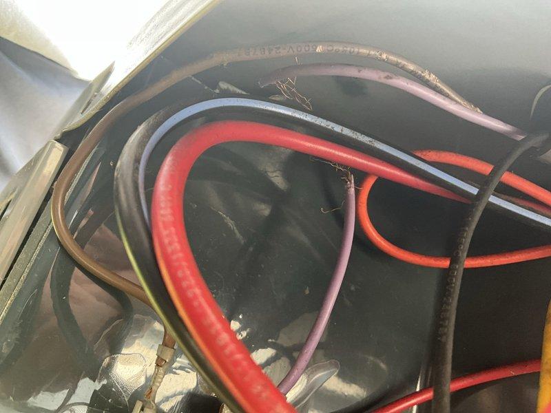 Responded to after hours service call for HVAC system malfunction. Upon arrival, inspected outdoor condensing unit and found electrical compartment accessible for diagnostics. Examined capacitor assembly and associated wiring connections, noting multiple color-coded electrical leads properly terminated to capacitor terminals. Verified all wire bundle connections secure with cable ties maintaining organized routing throughout electrical compartment. Inspected flexible ductwork connections at unit interface and confirmed proper seating. Evaluated indoor refrigerant line bundle routing through confined utility space, observing multiple service lines including supply, return, and drain configurations with brass fittings at connection points. All utility lines showed normal wear consistent with system age. Completed visual inspection of all accessible components, verified electrical connections tight, and confirmed system ready for operation. Unit returned to service.