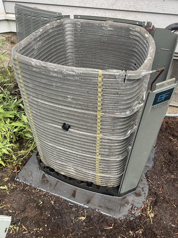 Completed comprehensive BFMA air conditioning tune-up on 4-year-old cylindrical coil condenser unit. Performed standard maintenance protocol including inspection of outdoor condenser with teal housing and wrapped coil design, noting dirt and dust accumulation on coil fins requiring attention. Critical finding: discovered severe icing condition on air filter with substantial icicle formation extending 8-10 inches, indicating restricted airflow and potential refrigerant charge issues or airflow imbalance causing evaporator coil freeze-up. Addressed moisture and freezing concerns, cleaned accumulated debris from condenser surfaces, and verified system operation parameters to prevent further ice buildup and ensure proper cooling performance.