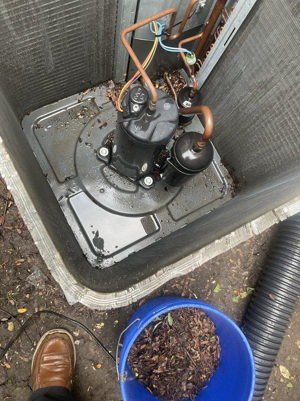 Completed comprehensive AC tune-up maintenance on outdoor condensing unit. Removed significant accumulation of leaves, organic debris, and decomposed material from compressor compartment and base pan that had restricted airflow. Inspected refrigerant lines, electrical connections, and condenser coils; verified all components operating within normal parameters.