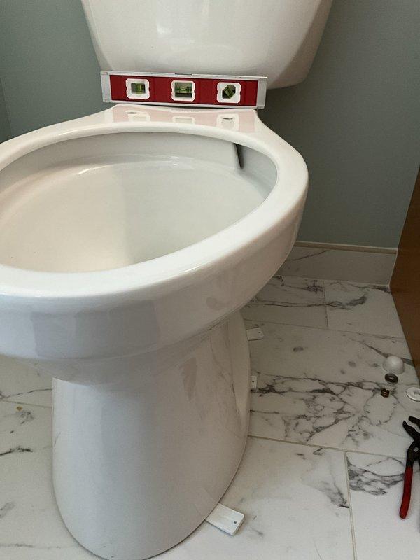 Installed new toilet over existing brass flange on marble-patterned tile floor, ensuring proper leveling and secure mounting to waste pipe connection. Following toilet installation, installed customer-provided bidet toilet seat with all necessary supply lines, fittings, and connections to ensure full operational functionality of the integrated bidet system.