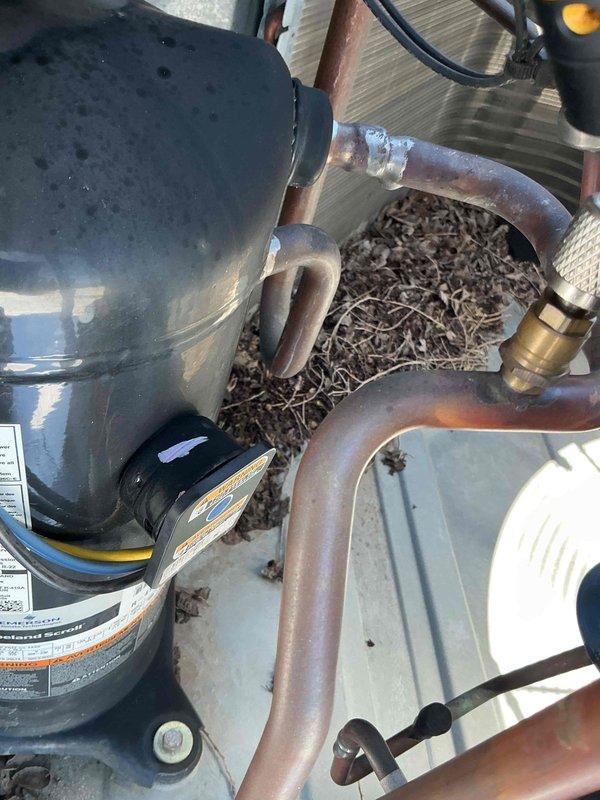 # Commercial HVAC No Cooling Service Call

Responded to commercial tenant facility reporting no cooling condition on rooftop packaged HVAC unit. Upon arrival, accessed unit and performed visual inspection of major components. Found significant accumulation of organic debris including leaves, twigs, and plant material around compressor and refrigerant lines, indicating lack of recent maintenance.

Conducted electrical diagnostics using digital multimeter to verify compressor operation and electrical supply. Inspected copper refrigerant lines showing weathering and oxidation consistent with 16-year-old equipment. Verified all electrical connections and wiring integrity. Checked compressor specifications and safety labels for proper operating parameters.

Documented equipment condition with photographs showing compressor compartment, refrigerant piping configuration, and debris accumulation affecting unit performance. Cleared organic debris from equipment platform and around copper lines 