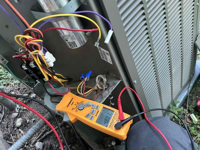 Responded to after hours emergency call for HVAC system failure. Upon arrival, performed diagnostic testing on outdoor condensing unit using digital multimeter. Testing revealed failed run capacitor reading 9.90 microfarads, significantly below manufacturer specifications. Capacitor showed visual signs of deterioration and electrical failure. Replaced defective dual run capacitor with OEM equivalent part, reconnected all electrical terminals, and verified proper wire connections. Tested system operation and confirmed compressor and condenser fan motor startup within normal parameters. Inspected indoor air handler unit and condensate pump assembly in basement for related issues. Verified condensate pump operation, checked PVC drain line routing, and confirmed proper drainage. System restored to full operational status with all components functioning normally.