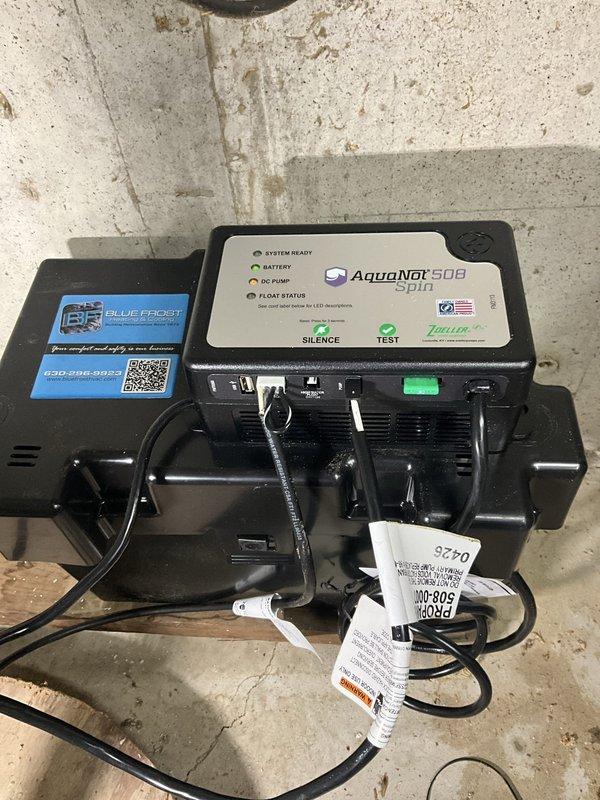 Replaced existing backup sump pump system with new AquaNot 508 Spin battery-powered backup unit. The backup pump was installed adjacent to the primary submersible pump in the existing sump basin to provide redundant drainage protection in the event of primary pump failure or power outage. System tested and verified operational with all indicator lights functioning properly on the control panel.