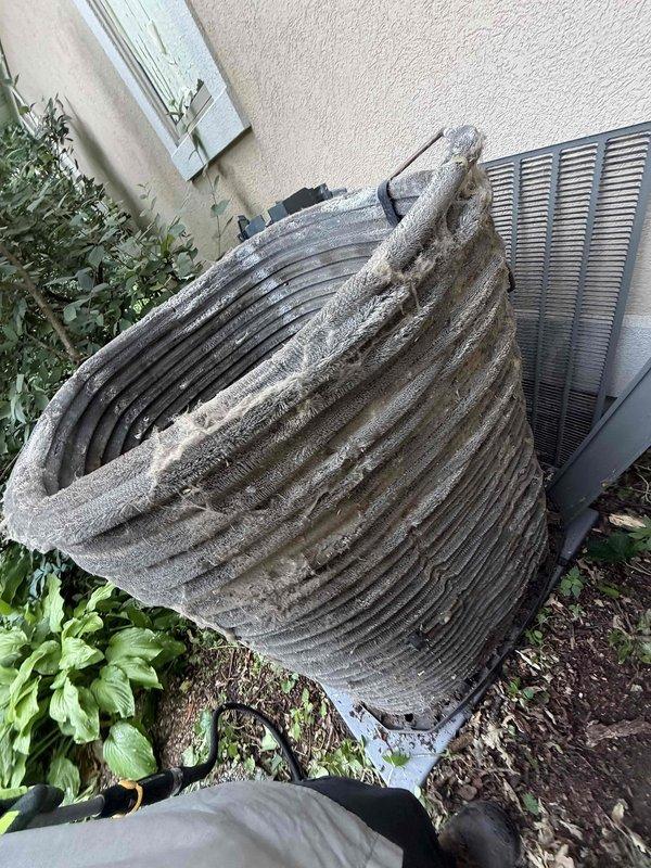 Completed comprehensive air conditioning tune-up on 8+ year old system with morning service window. Performed full system inspection of indoor and outdoor components, including evaporator coil assessment in basement utility area and thorough evaluation of outdoor condenser unit. Condenser coil exhibited heavy accumulation of dirt, dust, and debris on fins, requiring extensive cleaning to restore proper airflow and heat transfer efficiency. Cleaned condenser coils, checked refrigerant levels, inspected electrical connections, tested capacitors, and verified proper system operation. Unit restored to optimal performance with improved airflow through cleaned coil surfaces.