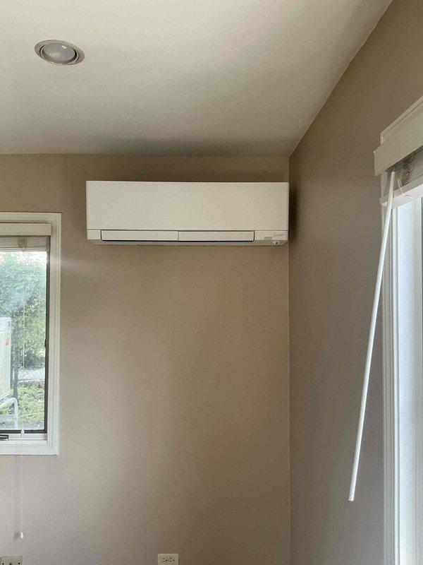 Completed installation of Mitsubishi Hyper Heat mini-split system in sunroom, including MUZ-FX15NLHZ outdoor unit and MSZ-FX15NL indoor wall-mounted unit. Installed outdoor unit on pad with stand, ran 50' line set (1/4" x 1/2") with flare fittings through attic to exterior, and mounted indoor head unit high on wall corner. Removed existing wall heater and capped appropriately, coordinated with customer's electrical contractor for 20A 2-pole breaker installation, and completed all refrigerant connections and system startup.