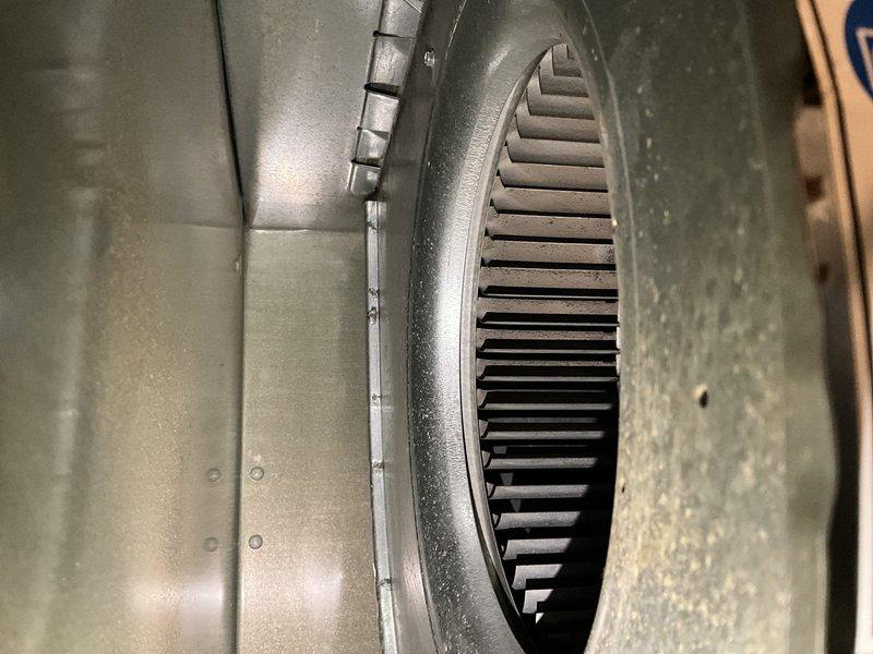 Completed comprehensive BFMA tune-up service on a 10-year-old residential air conditioning system. Performed full system inspection of outdoor condenser unit and indoor air handler components, including thorough examination of blower wheel assembly and ductwork. Inspected squirrel cage blower fan with cylindrical blade configuration, noting normal operational dust accumulation on blades and housing. Verified proper blower wheel rotation and clearances within metallic ductwork assembly. Examined outdoor condenser unit positioned on concrete pad, checking refrigerant lines, electrical disconnect, and conduit connections. Assessed condenser coil condition through vertical louvered panels and confirmed adequate airflow clearances around unit perimeter. Documented equipment condition through photographic records showing functional blower assembly with uniform blade spacing and well-maintained exterior condenser unit. All components operating within normal parameters for equipment age, with 
