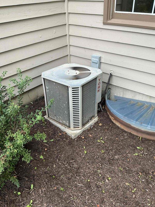 Conducted comprehensive evaluation of existing HVAC system for new homeowner requesting replacement estimate. Inspected indoor furnace unit with attached evaporator coil located in basement mechanical room, noting flexible insulated ductwork connections and electrical components. Assessed outdoor York brand condensing unit positioned on concrete pad against exterior wall, examining condition of unit housing, fan grille, and electrical disconnect. Documented current system configuration including refrigerant line routing and overall installation setup. Provided detailed photographic documentation of both indoor and outdoor equipment for replacement proposal preparation.