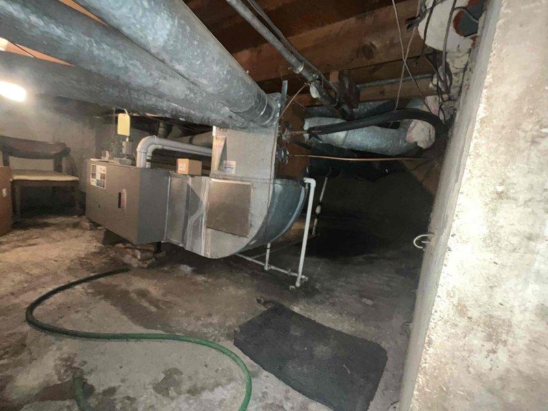 Responded to no cooling complaint on residential split system air conditioning unit. Upon arrival, customer reported unit was not cooling and believed it needed refrigerant. Unit is 15+ years old. Performed initial assessment of both indoor air handler located in basement and outdoor condensing unit. Observed outdoor unit surrounded by overgrown vegetation restricting airflow to condenser coils. Turned system off per customer request. Advised customer of age of equipment and need for proper diagnostic service to determine root cause of cooling failure, which may include refrigerant leak detection, electrical testing, and comprehensive system evaluation before any refrigerant can be added.