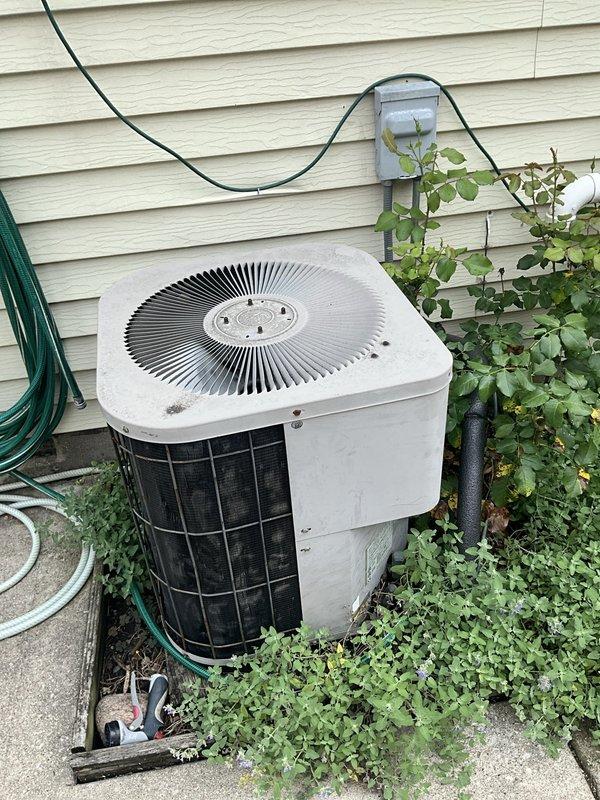 Responded to no cooling complaint on residential split system air conditioning unit. Upon arrival, customer reported unit was not cooling and believed it needed refrigerant. Unit is 15+ years old. Performed initial assessment of both indoor air handler located in basement and outdoor condensing unit. Observed outdoor unit surrounded by overgrown vegetation restricting airflow to condenser coils. Turned system off per customer request. Advised customer of age of equipment and need for proper diagnostic service to determine root cause of cooling failure, which may include refrigerant leak detection, electrical testing, and comprehensive system evaluation before any refrigerant can be added.