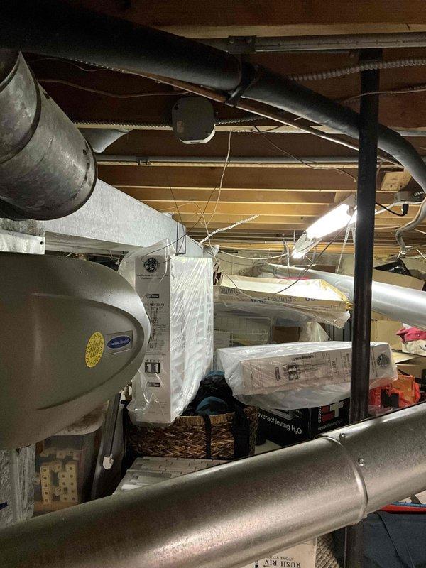 Conducted comprehensive full system HVAC estimate at residential property. Evaluated existing outdoor air conditioning unit showing significant age-related deterioration including extensive rust staining on top panel and weathered components, indicating need for replacement. Inspected basement mechanical area and assessed existing ductwork configuration including metallic supply ducts and flexible return duct system suspended from floor joists. Documented water heater location and existing HVAC infrastructure layout to determine proper equipment sizing and installation requirements. Photographed exterior condensing unit positioned on concrete pad adjacent to home and interior mechanical space to provide accurate proposal for complete system replacement including new furnace and air conditioning equipment.