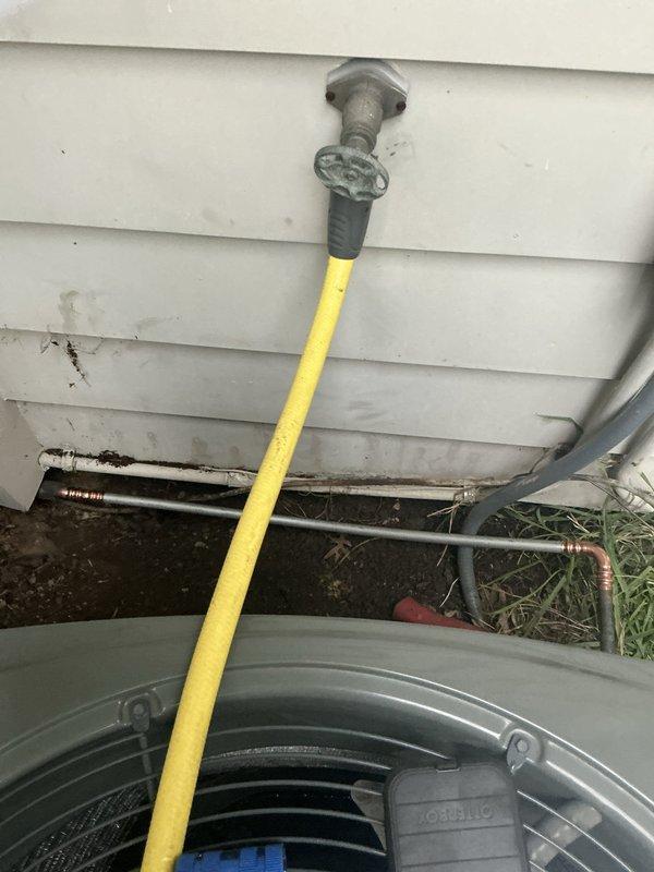 Performed pump down procedure and located refrigerant leak on outdoor line set using UV dye tracing. Identified leak point at section of line set immediately before underground transition, with dye evidence documented in photos. Isolated refrigerant system and removed compromised line set section to prepare for repair, addressing the active leak that was compromising system performance.