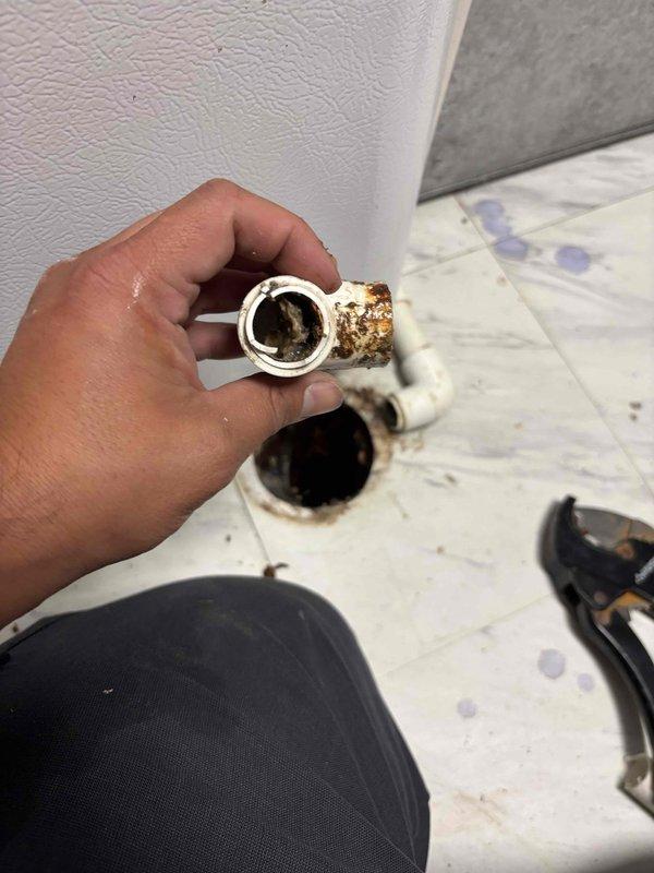 Responded to water leak complaint at residential HVAC system. Upon inspection, identified severely corroded PVC condensate drain fitting at furnace unit causing water discharge onto floor. Removed deteriorated drain components showing extensive rust and corrosion buildup that compromised drainage integrity. Replaced failed PVC drain fitting and associated hardware to restore proper condensate removal and eliminate active leak condition.