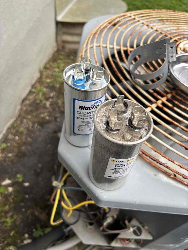 Responded to no cooling call at residential property. Upon inspection, found failed dual-run capacitor exhibiting severe corrosion and deterioration, preventing compressor and condenser fan operation. Removed defective TITAN capacitor and installed new BlueFin replacement with proper microfarad rating. Cleared accumulated debris including leaves and organic material from unit interior. Tested system operation, verified proper compressor startup, confirmed adequate airflow from condenser fan, and restored cooling functionality before client's departure.