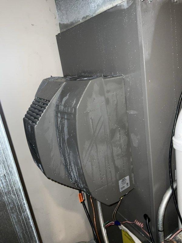 # HVAC Service Report - No Cooling Call

Responded to emergency no cooling call for one-month-old residential air conditioning system. Upon arrival, performed visual inspection of air handler unit located in attic space. Found extensive frost and ice buildup on evaporator coil with heavy condensation throughout cabinet interior, indicating restricted airflow condition.

Identified drum-style humidifier installed on supply ductwork with visible moisture trails and water streaking on exterior housing. Further investigation revealed frozen evaporator coil preventing proper heat exchange and air circulation through system. Documented conditions with photographic evidence showing crystalline frost accumulation covering coil surfaces and moisture damage to cabinet walls.

Diagnosed cause as severely restricted airflow to evaporator coil, likely due to combination of factors including possible filter restriction, improper humidifier installation affecting duct airflow, or ductwork configurati