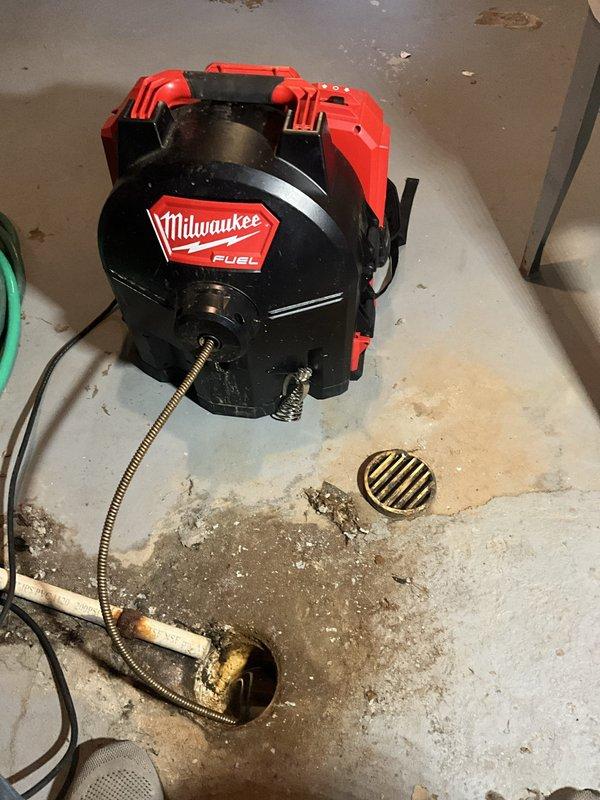 Removed p-trap from basement utility sink to gain access to the drainage system. Deployed power auger with flexible cable to rod the branch line in an attempt to clear the blockage affecting the floor drain. Blockage resistance encountered during rodding process, and standard mechanical snaking procedures were performed to restore drainage flow.