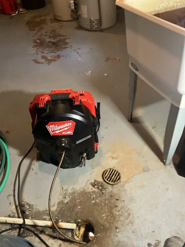 Removed p-trap from basement utility sink to gain access to the drainage system. Deployed power auger with flexible cable to rod the branch line in an attempt to clear the blockage affecting the floor drain. Blockage resistance encountered during rodding process, and standard mechanical snaking procedures were performed to restore drainage flow.