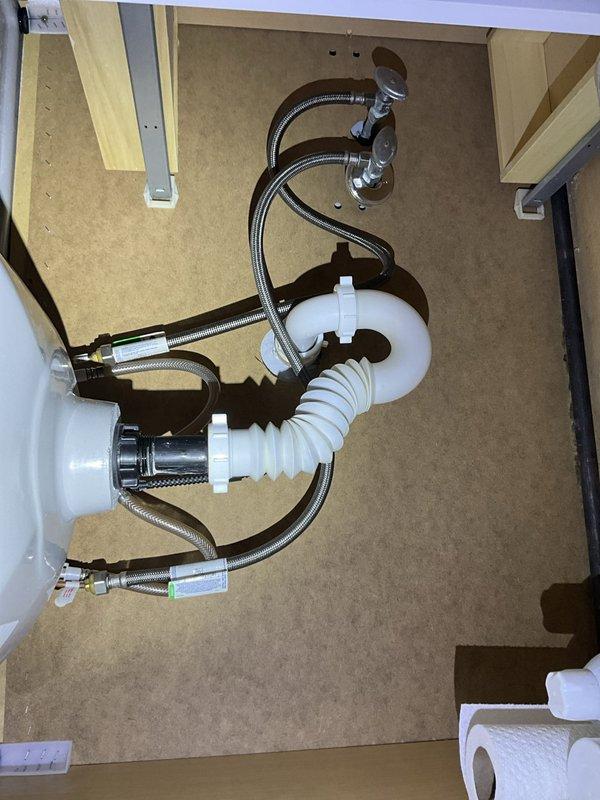 Completed comprehensive new client plumbing inspection of residential property. Evaluated bathroom sink plumbing installation including flexible braided stainless steel supply lines, chrome compression fittings, and white corrugated S-trap drain assembly—all components found in good condition with no visible leaks or corrosion. Inspected kitchen plumbing system including stainless steel sink with chrome arcing faucet and countertop-mounted soap dispenser, verified proper water flow and drainage operation. Addressed client concern regarding sulfur odor in water supply, which typically indicates presence of hydrogen sulfide gas or sulfate-reducing bacteria in water system. Provided instruction on proper operation and maintenance of existing water softener system to client. Scheduled installation of new water filtration system to address water quality concerns. Documented all plumbing conditions with photographs for service records. All inspected plumbing fixtures and connections operatin