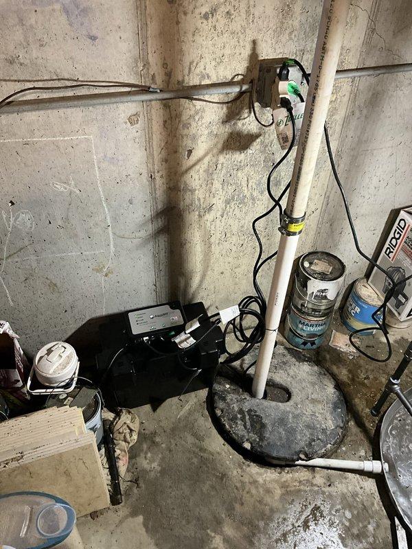 Removed and disposed of existing primary sump pump and backup battery system from basement location. Installed new primary sump pump with corrugated basin liner in existing concrete pit, ensuring proper positioning and secure mounting of pump mechanism. Connected new backup battery system with charger unit, routing all electrical connections to existing outlet box on basement wall. Installed and secured white PVC discharge piping vertically along wall to carry water away from foundation. Tested both primary and backup pump operation to verify proper function and water discharge. All equipment covered under 3-year warranty for pumps and charger, with 1-year warranty on battery and labor.