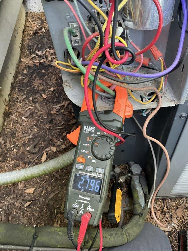 # HVAC Service Report - No Cooling Call

Responded to a no cooling complaint at a residential property. Upon arrival, performed diagnostic testing on the outdoor condensing unit using a digital multimeter to measure electrical values across the system's control circuits and connections. Multimeter displayed capacitance reading of 2196, indicating potential capacitor or electrical component issues affecting system operation.

Inspection revealed the outdoor unit's exterior casing in severely deteriorated condition, with protective covering material peeling away and hanging loose from multiple sections of the cabinet. This cosmetic damage, while not directly causing the no-cooling condition, exposes internal components to weather and debris infiltration that could lead to future operational problems.

Accessed the unit's electrical panel to examine wire connections, terminals, and control circuits. Multiple colored control wires (red, yellow, purple, orange, green, and pink) were inspect